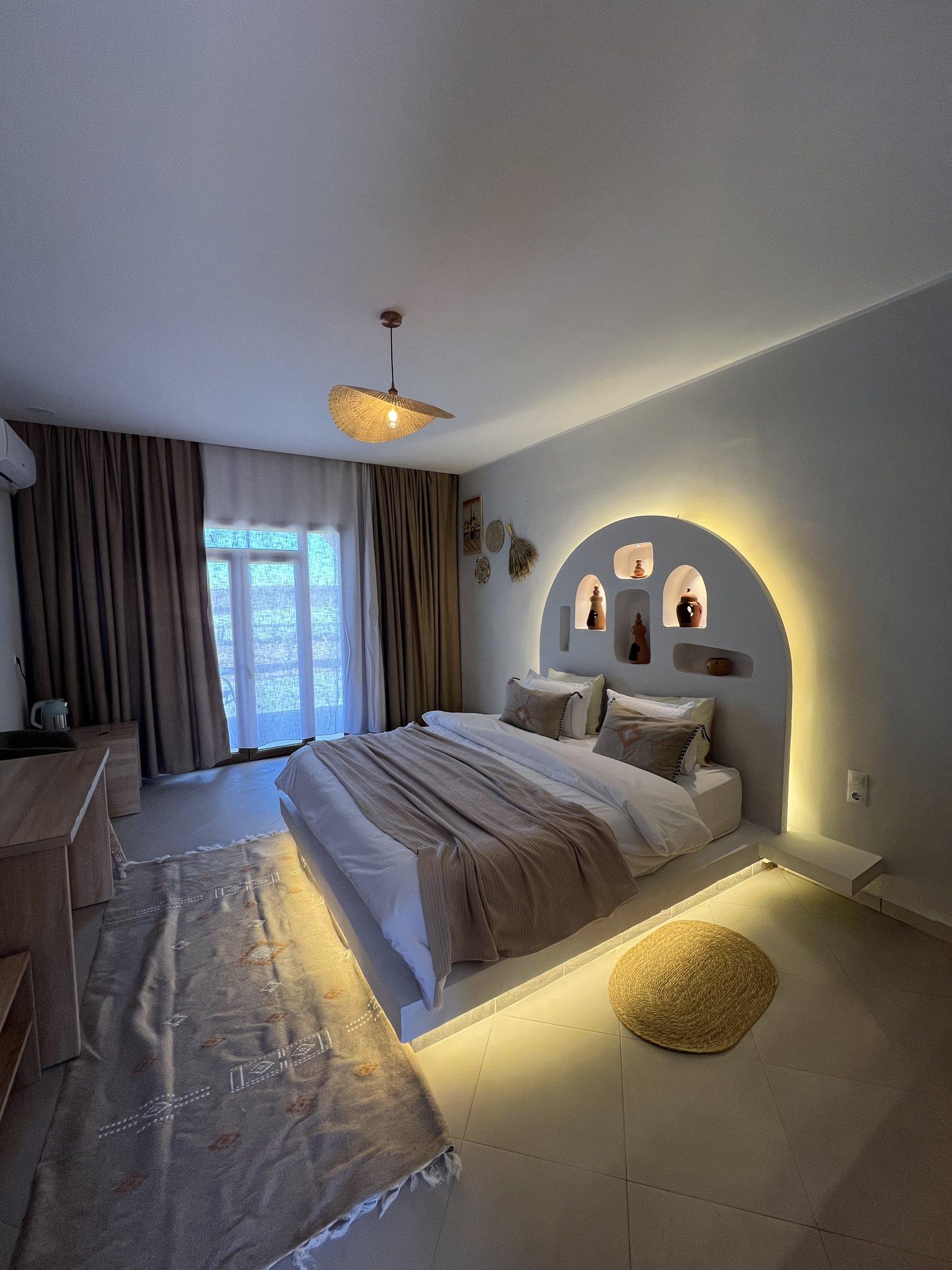Chambre Oasis — lit en alcôve, éclairage chaud et niche en pierre